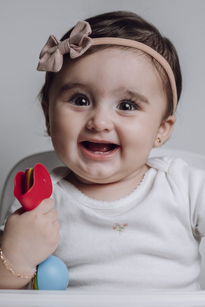 Charming portrait of a happy baby girl with a toy, capturing joyful innocence.